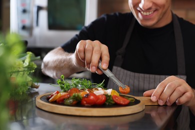 Photo of Professional chef decorating cooked dish in restaurant kitchen, closeup