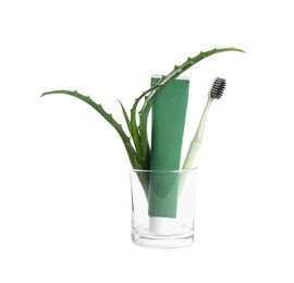 Tube of toothpaste, brush and aloe vera leaves in glass on white background