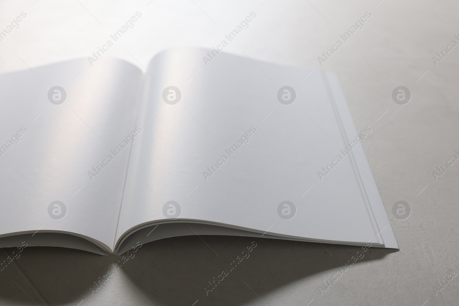 Photo of Open notebook with blank pages on grey textured table, closeup. Mockup for design