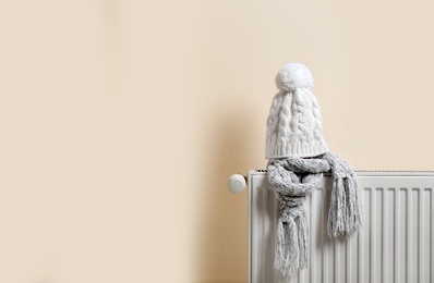 Photo of Knitted cap and scarf on heating radiator indoors