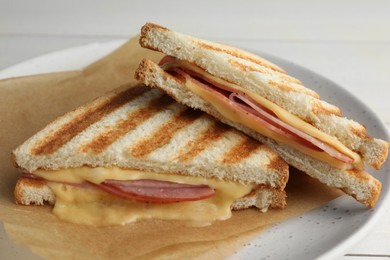 Photo of Tasty sandwiches with ham and melted cheese on white table, closeup