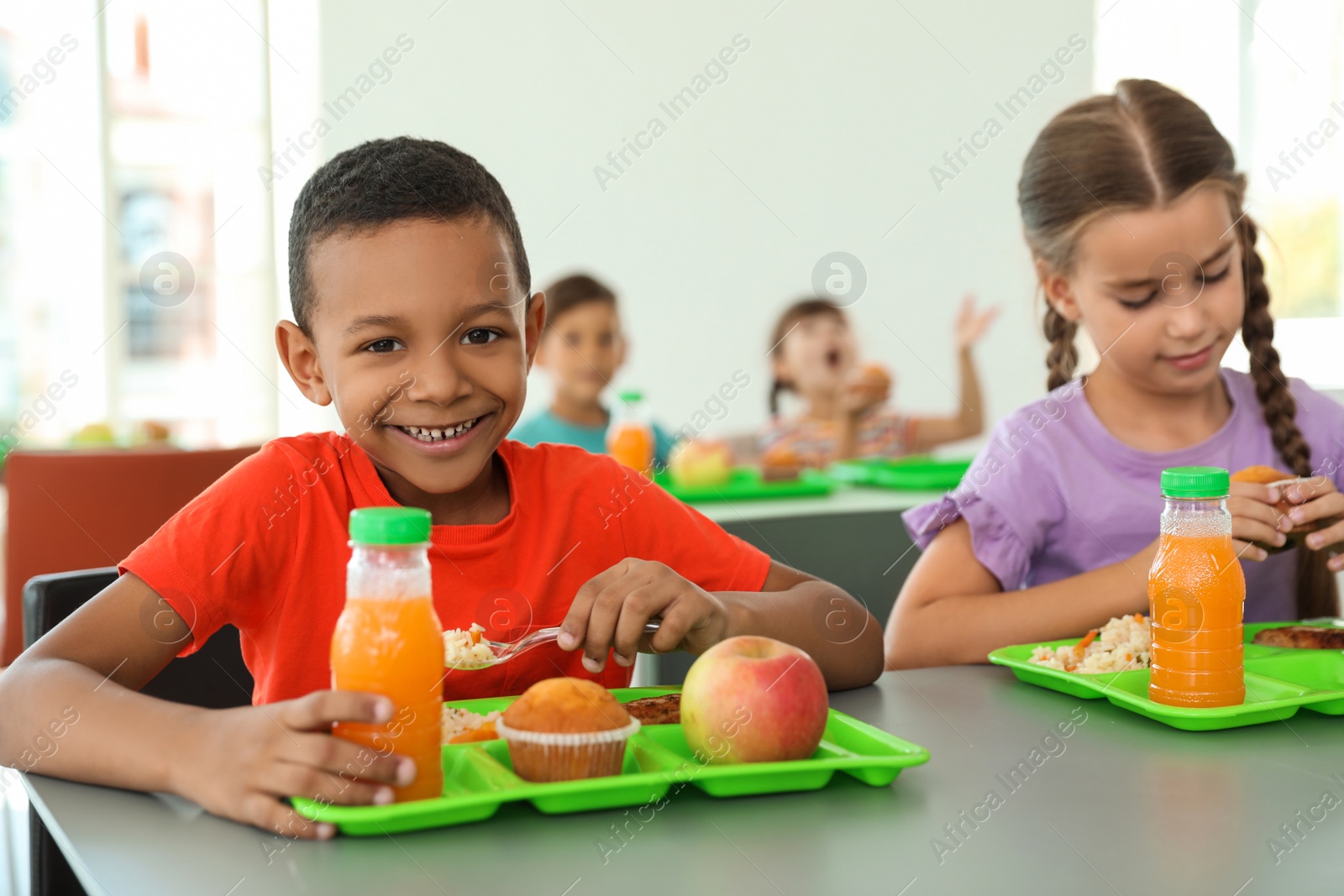 Photo of Children sitting at table and eating healthy food during break at school