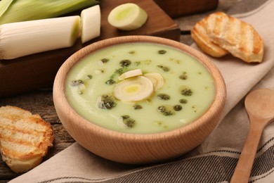 Photo of Delicious leek soup served on wooden table, closeup