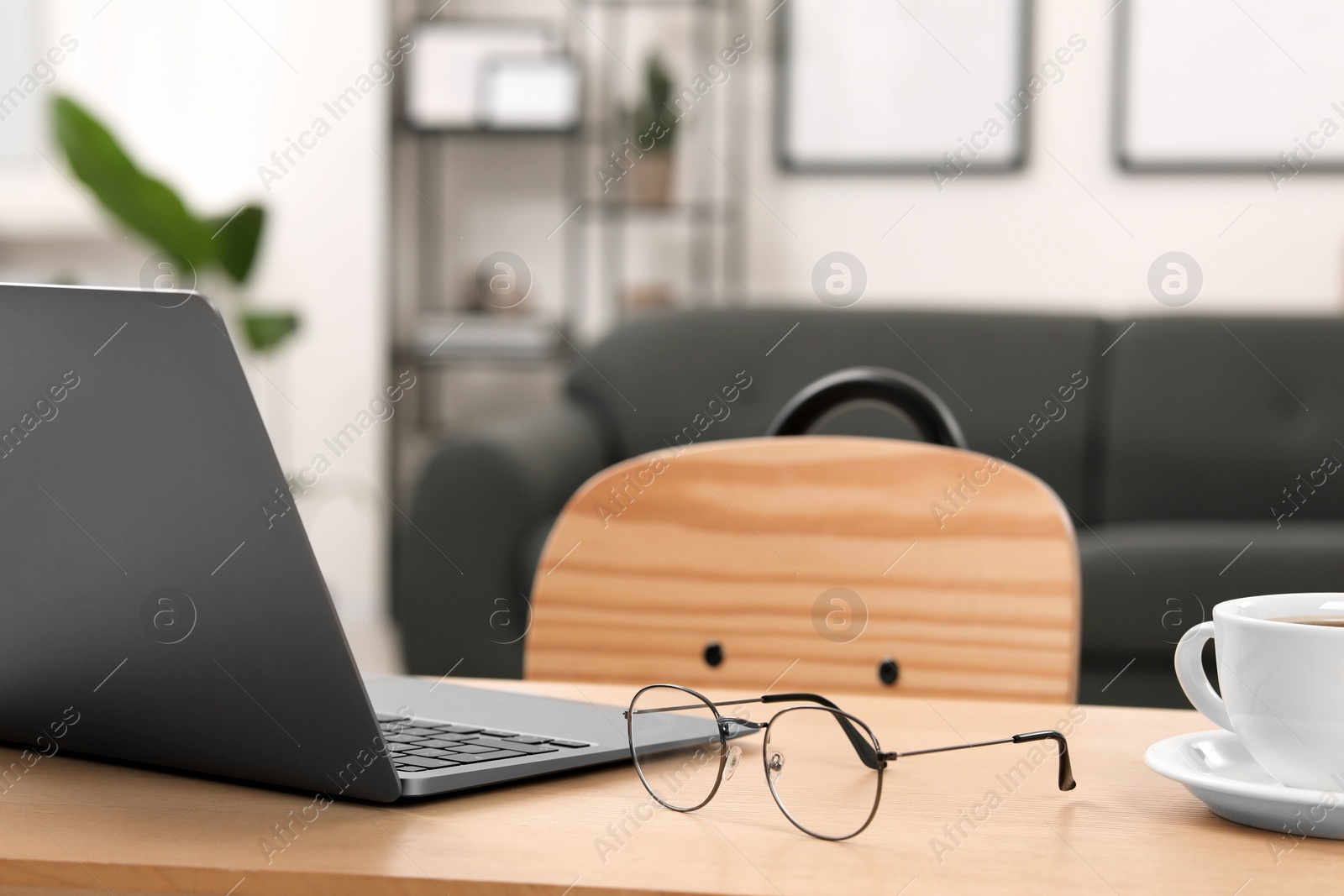 Photo of Home workspace. Laptop, glasses and cup of coffee on wooden desk in room. Space for text