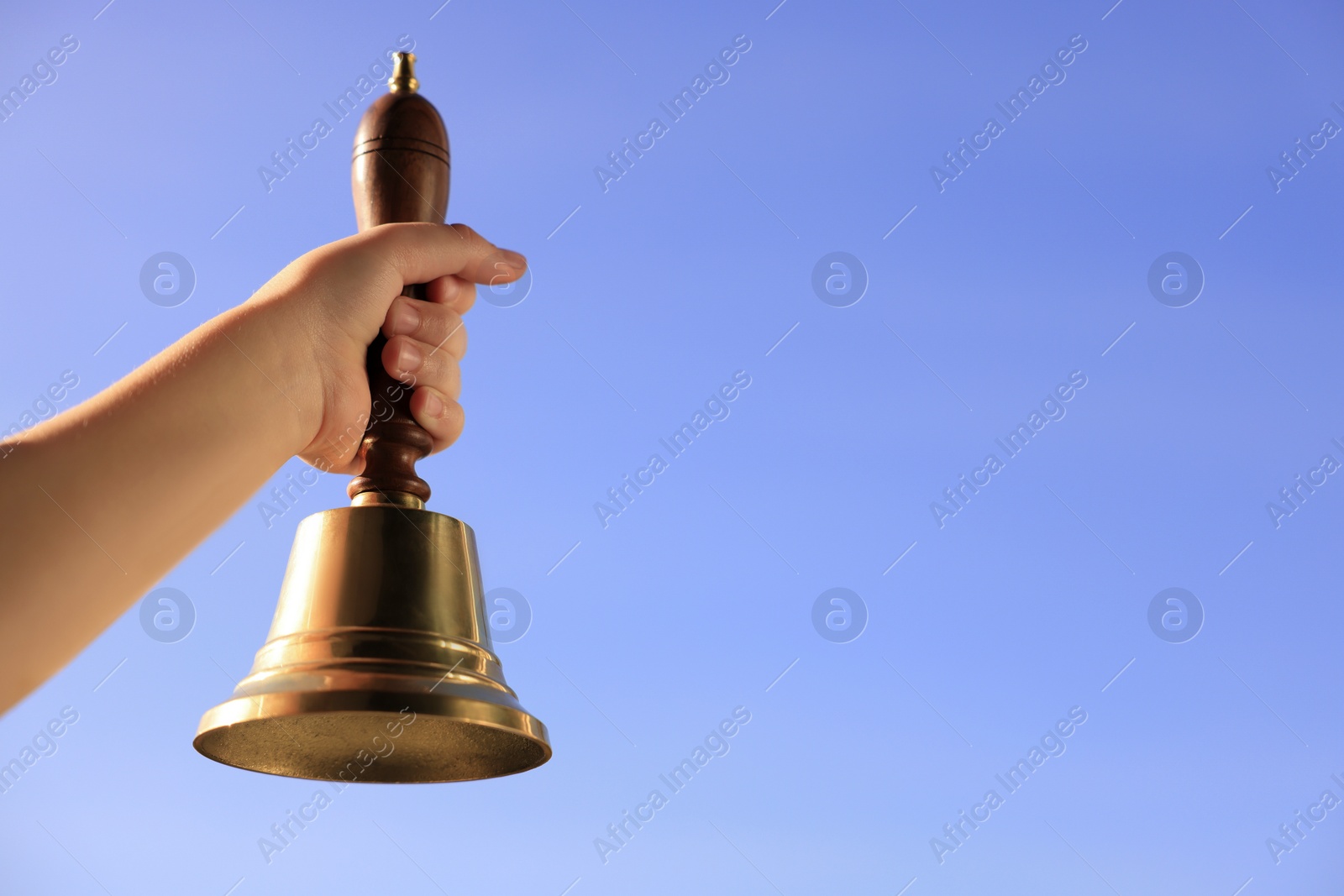 Photo of Pupil with school bell against beautiful sky, closeup. Space for text