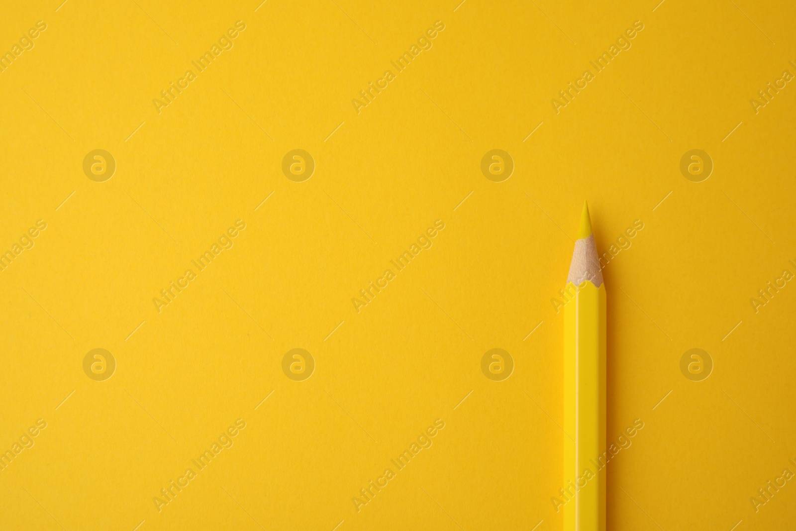 Photo of Wooden pencil on yellow background, top view. Space for text