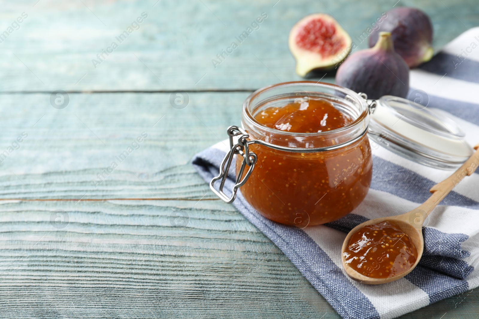 Photo of Homemade delicious fig jam on blue wooden table. Space for text