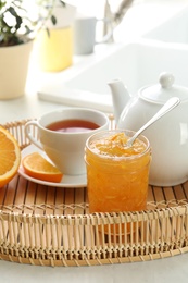 Photo of Delicious orange marmalade served with tea for breakfast in tray