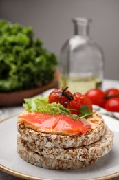 Photo of Crunchy buckwheat cakes with salmon, tomatoes and greens on plate, closeup