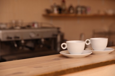 Cups of fresh aromatic coffee on table against blurred background. Space for text