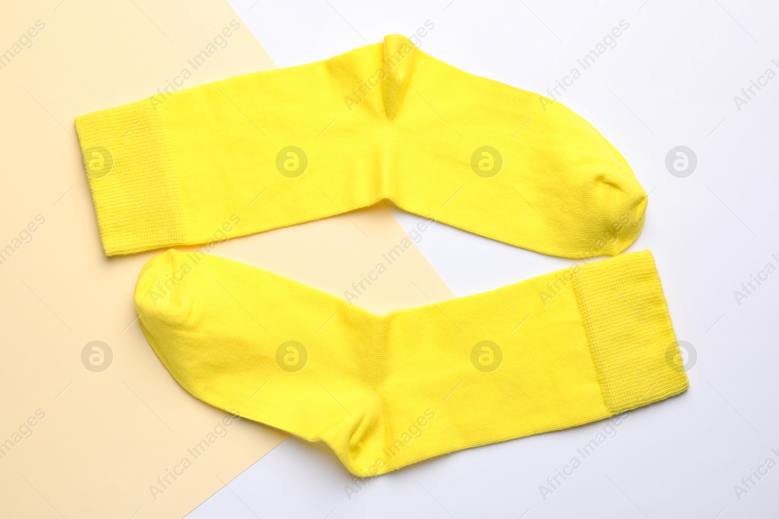 Photo of Pair of new yellow socks on color background, flat lay