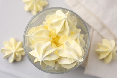 Photo of Tasty meringue cookies in glass on white tiled table, top view