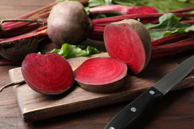 Photo of Cut raw beet and knife on wooden table