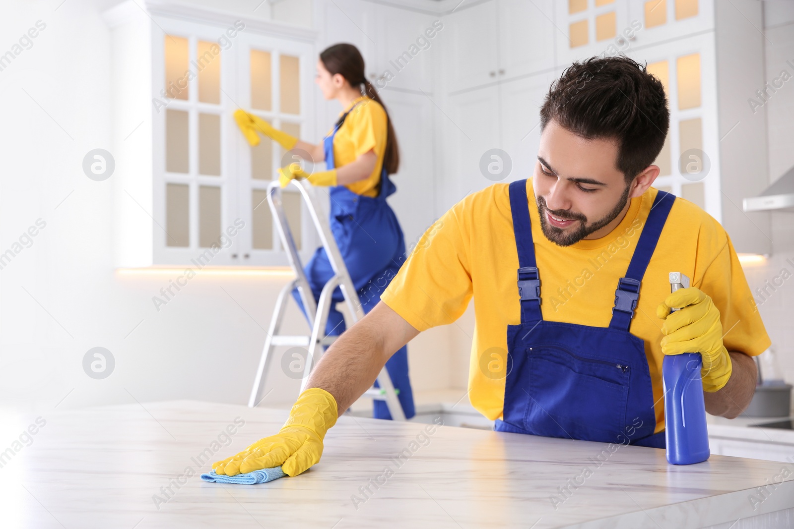 Photo of Professional young janitor cleaning table in kitchen