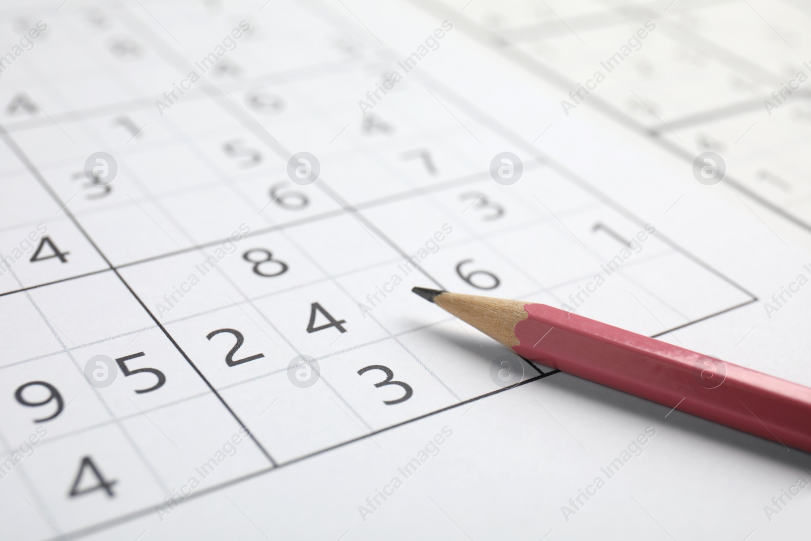 Photo of Sudoku puzzle grid and pencil, closeup view