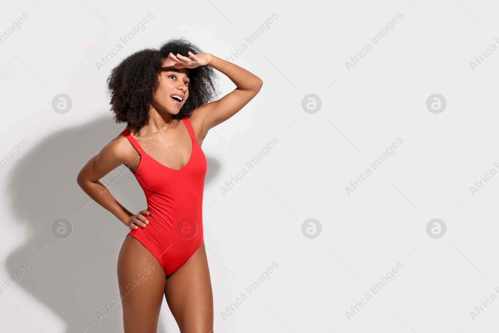 Photo of Beautiful woman in red one-piece summer swimsuit on white background, space for text