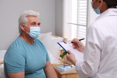 Photo of Doctor examining senior man with protective mask at nursing home