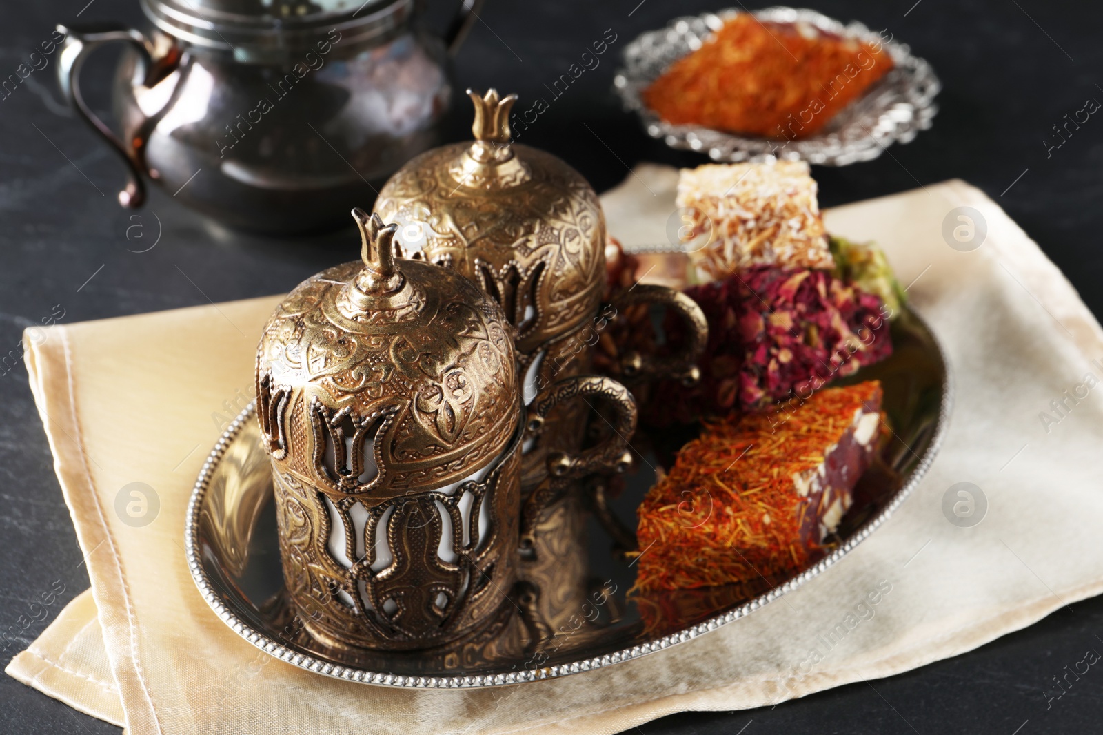 Photo of Tea and Turkish delight served in vintage tea set on dark grey textured table