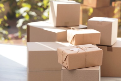 Photo of Parcel with tag and blurred stacked boxes on background, indoors