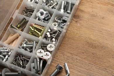 Organizer with many different fasteners on wooden table, above view. Space for text