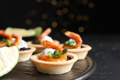 Photo of Delicious canapes with shrimps and black caviar on black table, closeup