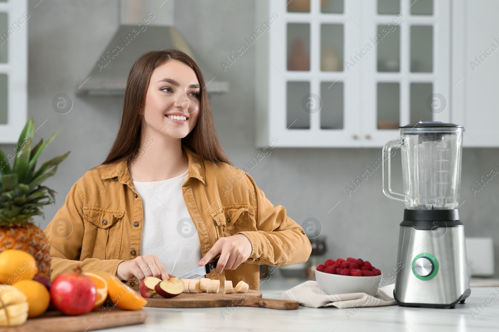 Photo of Woman preparing ingredients for tasty smoothie at white marble table in kitchen