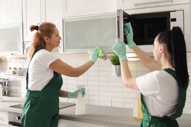 Photo of Teamprofessional janitors cleaning kitchen indoors