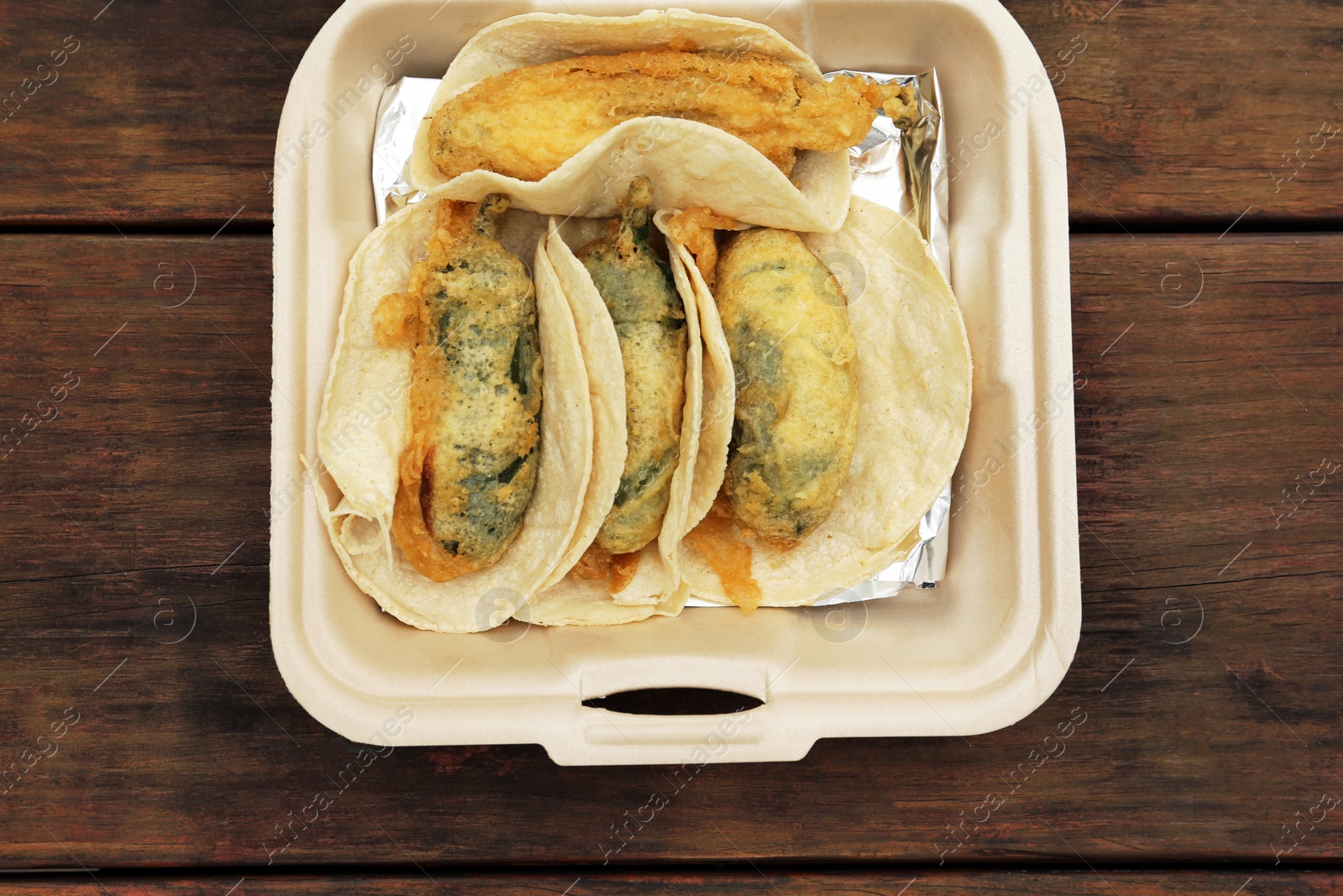 Photo of Jalapeno peppers stuffed with cheese in box on wooden table, top view