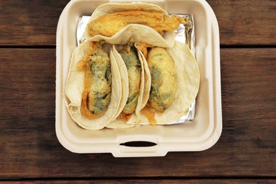 Photo of Jalapeno peppers stuffed with cheese in box on wooden table, top view