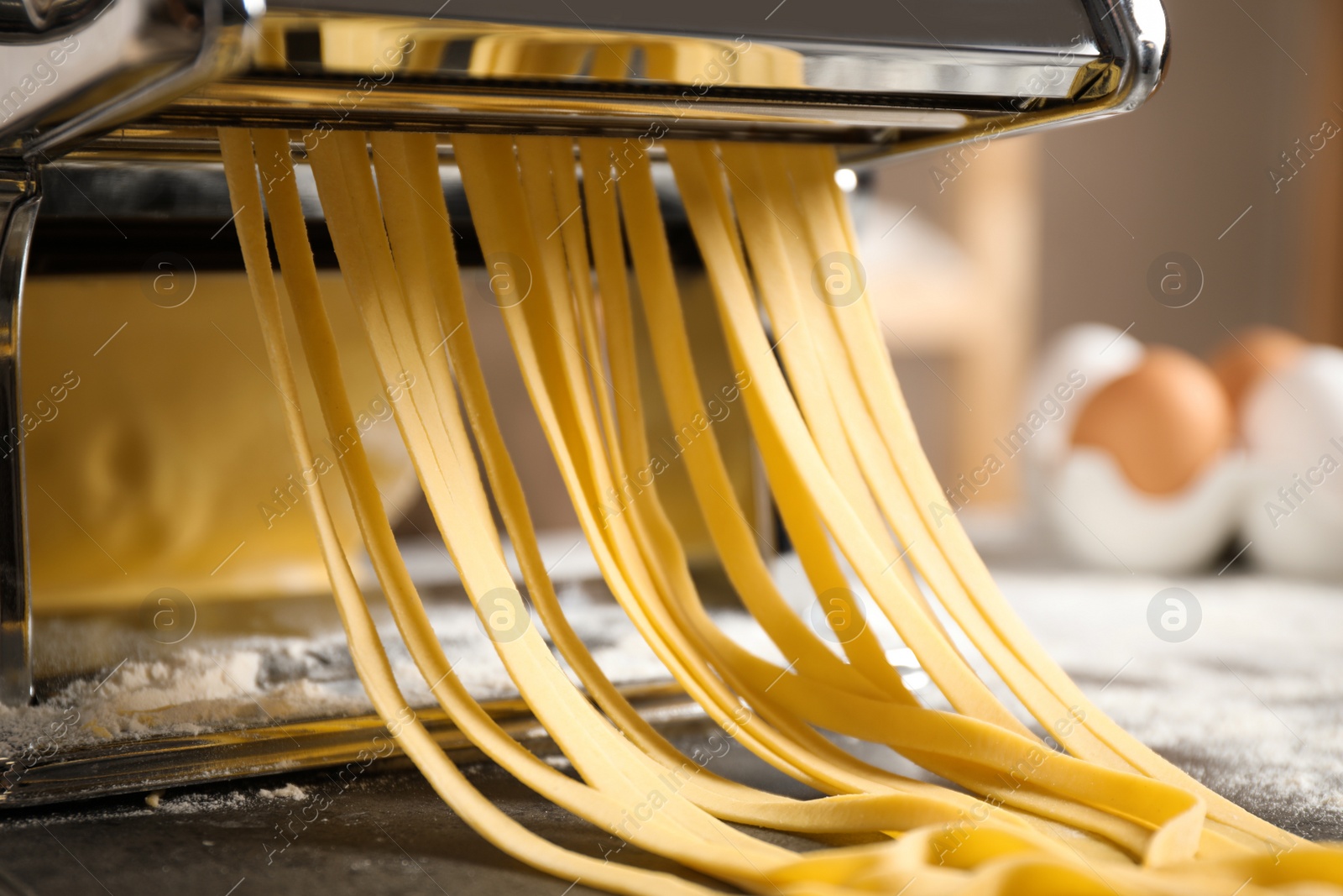 Photo of Pasta maker machine with dough on grey table, closeup