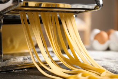 Pasta maker machine with dough on grey table, closeup