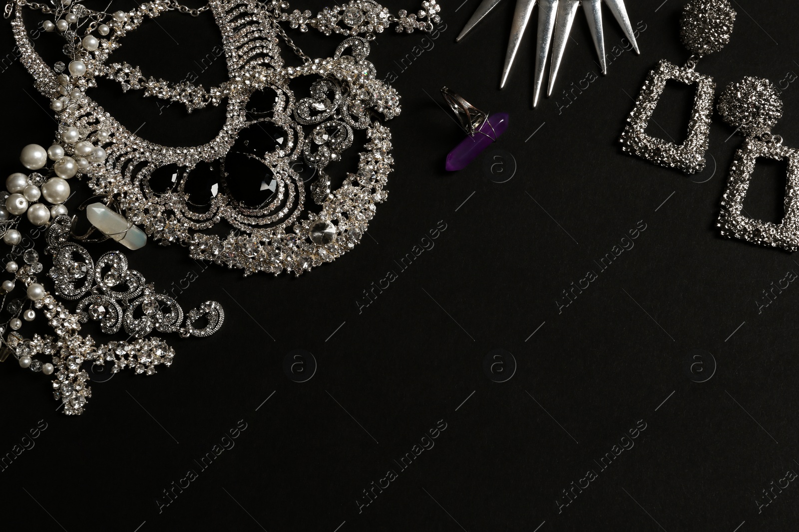 Photo of Different elegant jewelry on black background, top view. Space for text