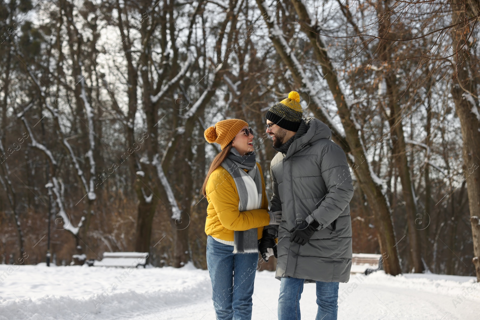 Photo of Beautiful happy couple walking in snowy park on winter day