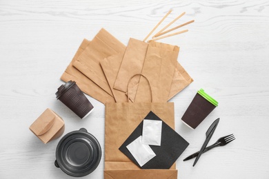 Flat lay composition with paper bags and different takeaway items on wooden background. Space for design