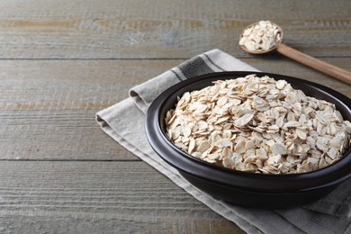 Photo of Bowl of oatmeal and spoon on wooden table. Space for text