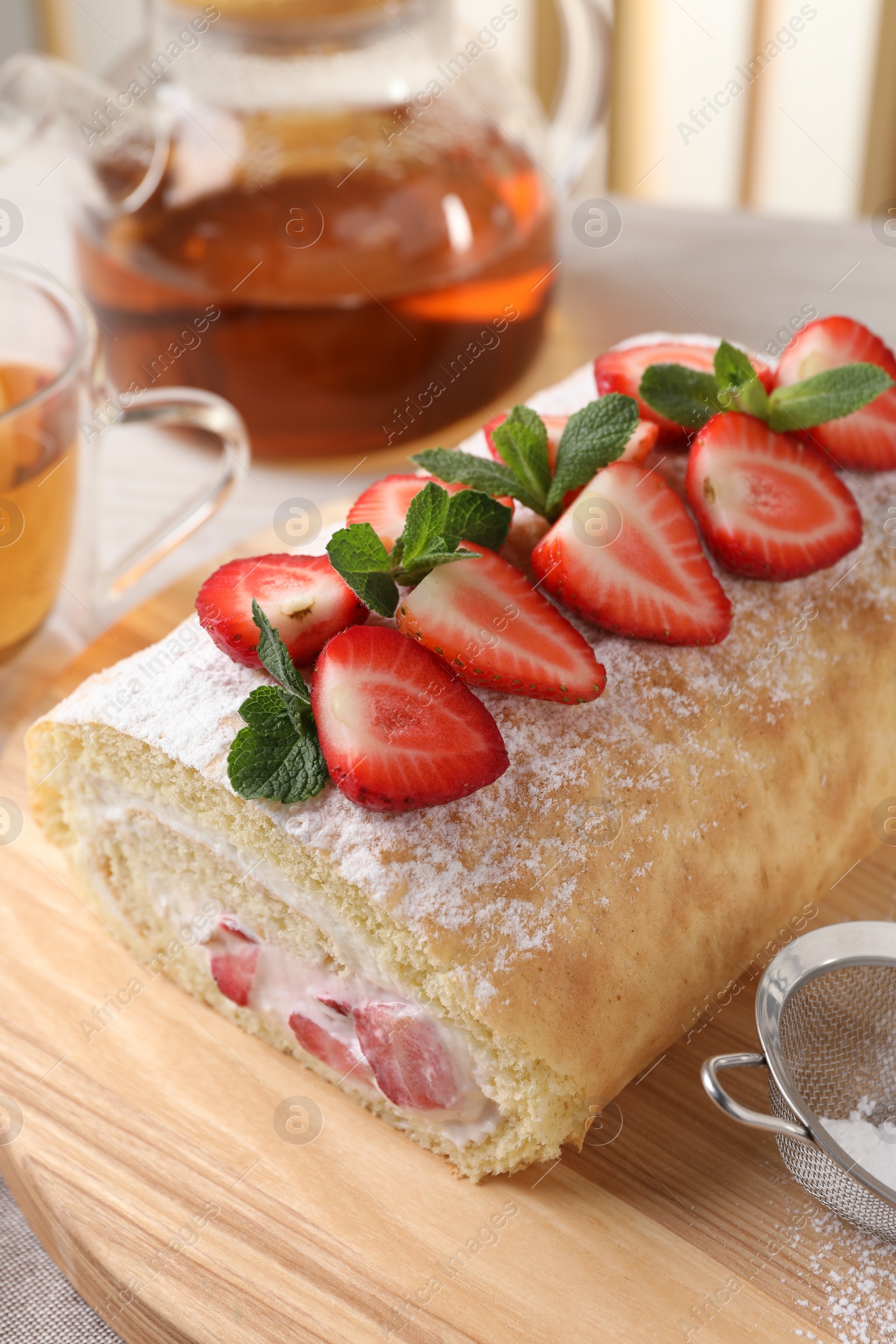 Photo of Delicious cake roll with strawberries and cream on wooden board, closeup