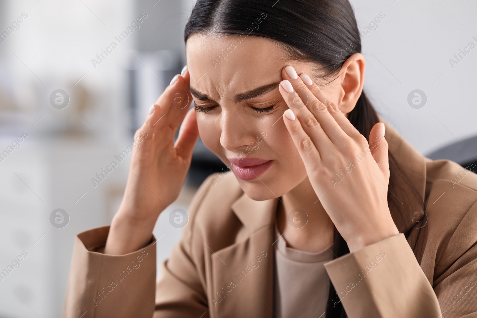 Photo of Woman suffering from headache at workplace in office