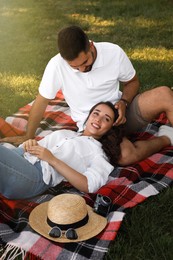 Photo of Lovely couple resting on picnic plaid in summer park