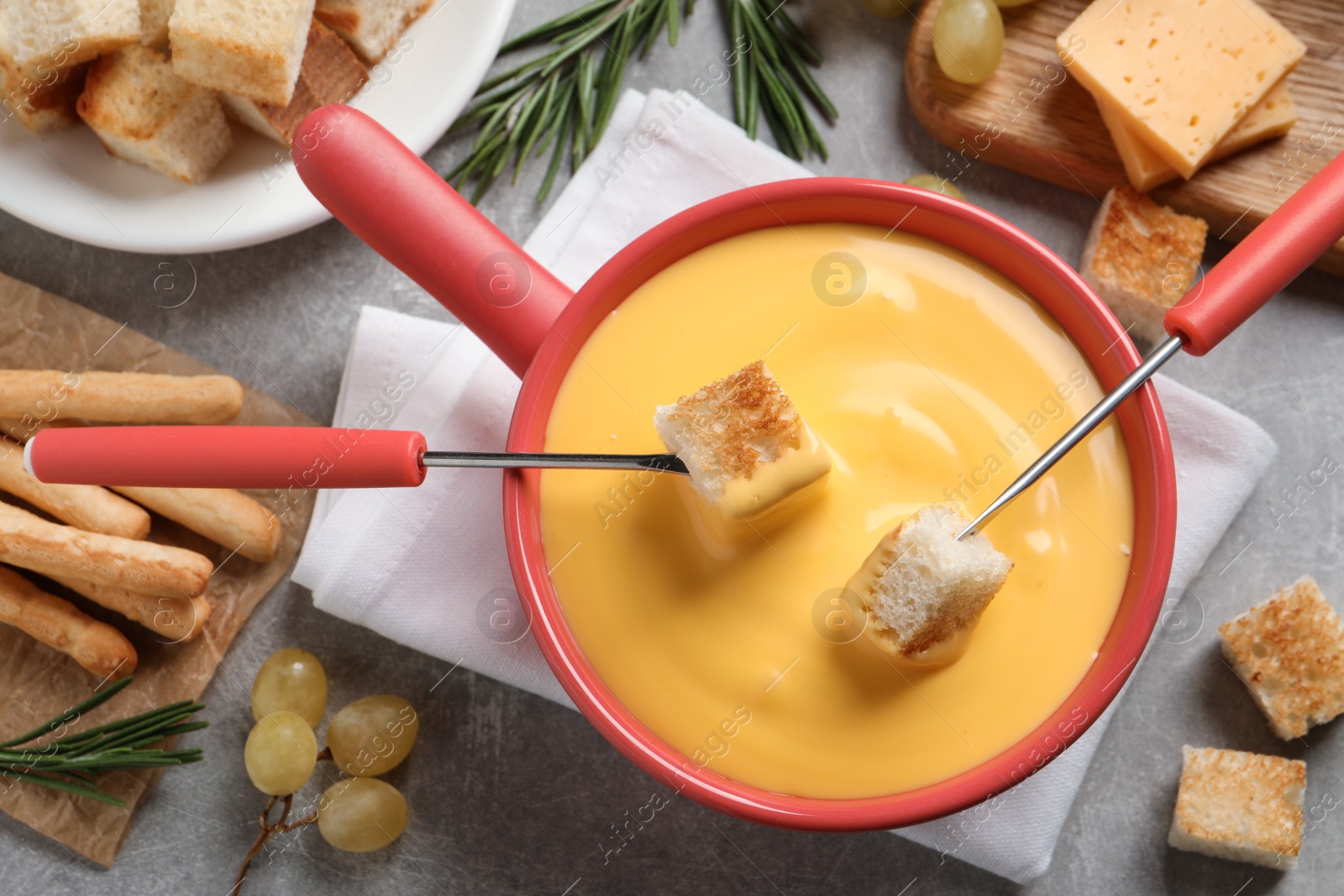 Photo of Flat lay composition with pot of tasty cheese fondue on grey table