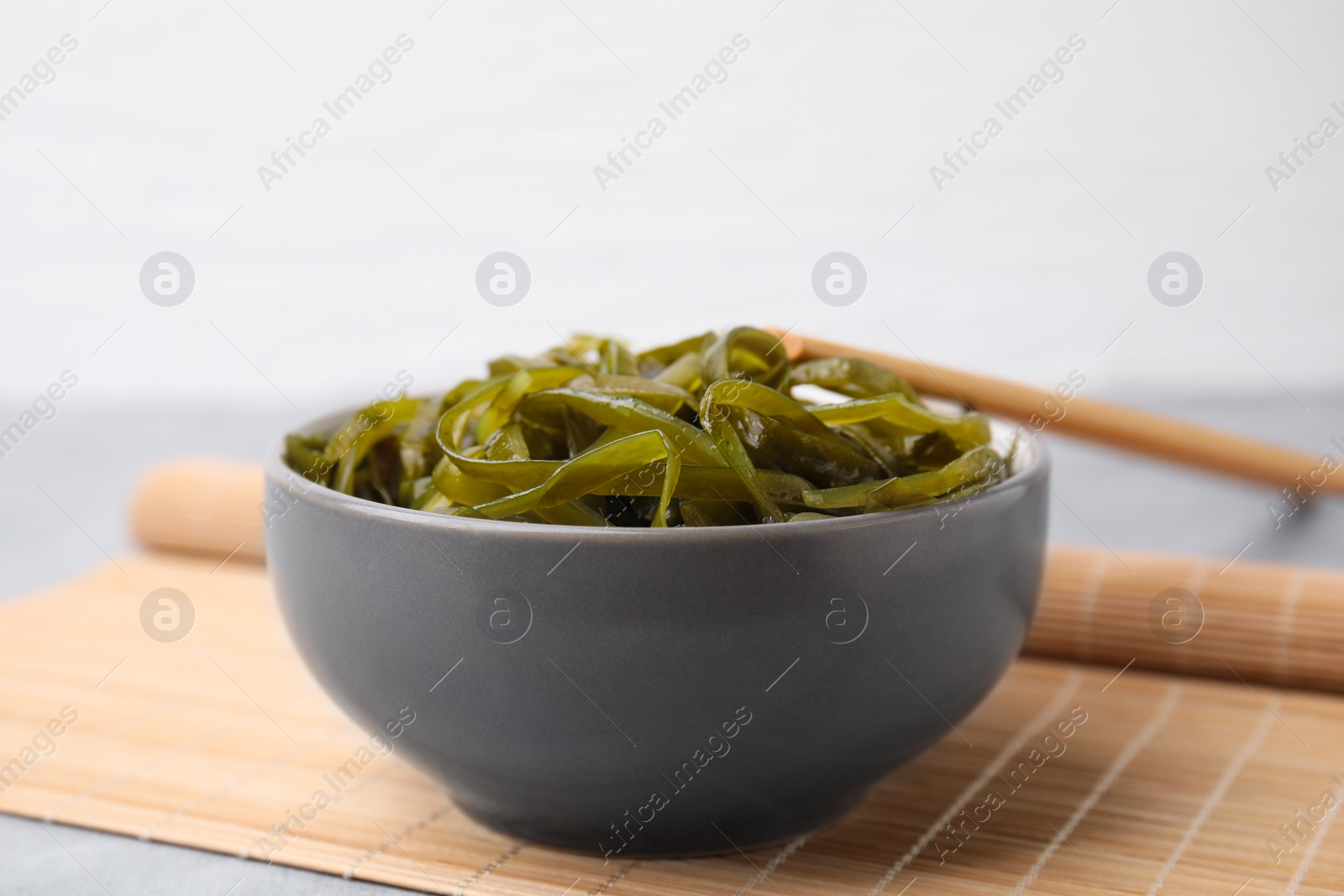 Photo of Tasty seaweed salad in bowl served on gray table, closeup