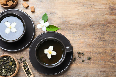 Photo of Flat lay composition with tea and fresh jasmine flowers on wooden table. Space for text