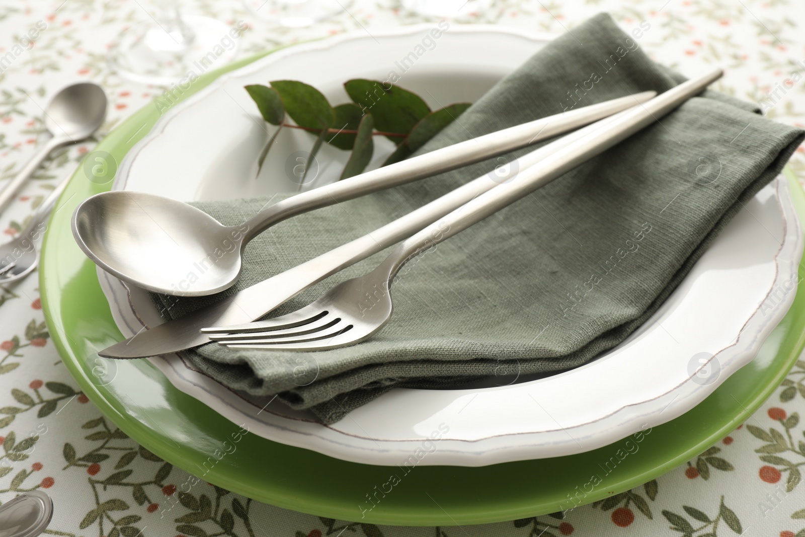 Photo of Stylish setting with cutlery, plates, napkin and floral decor on table, closeup