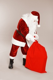 Photo of Authentic Santa Claus with bag full of gifts on grey background