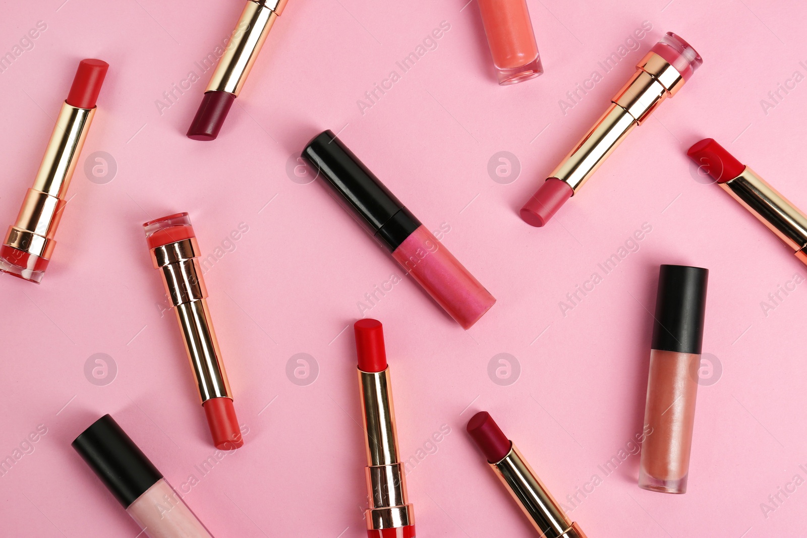 Photo of Set of bright lipsticks on pink background, flat lay