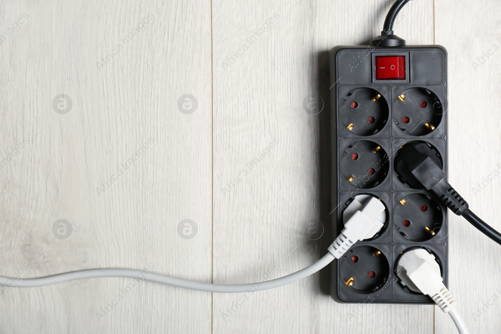 Photo of Extension cord on wooden floor, top view with space for text. Electrician's equipment