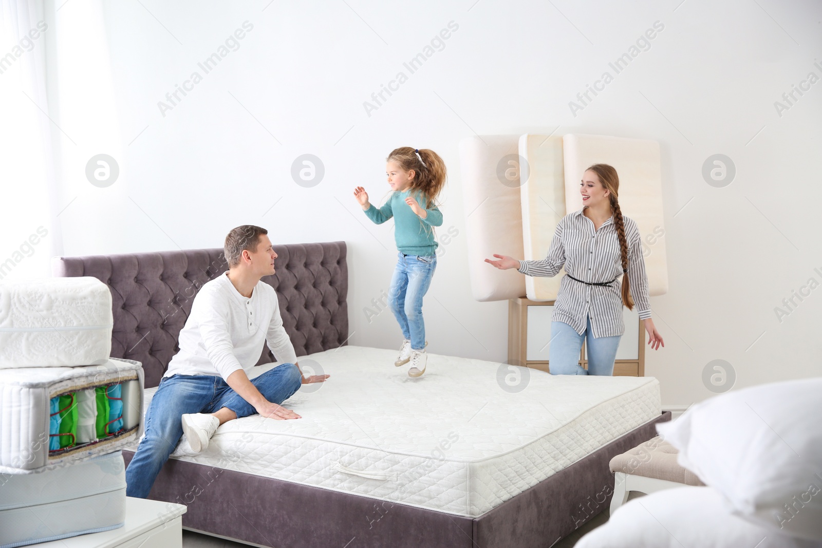 Photo of Happy family choosing mattress in furniture store