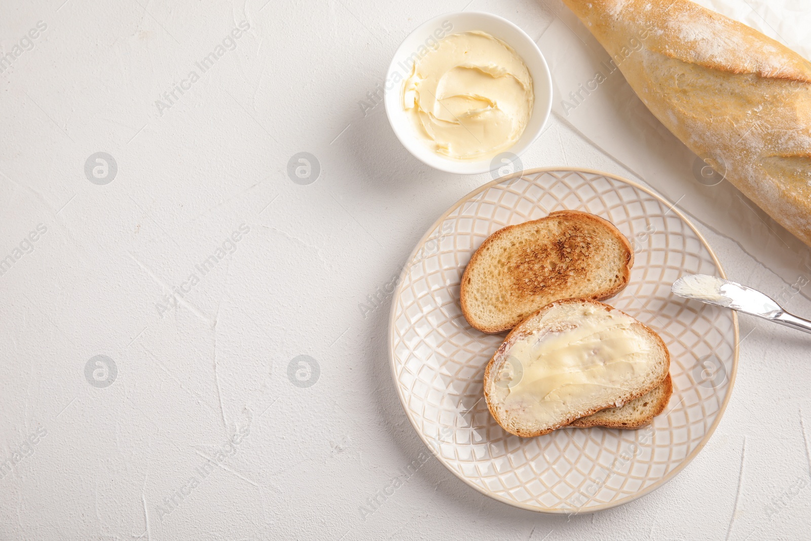 Photo of Tasty bread with butter served for breakfast on white table, top view. Space for text