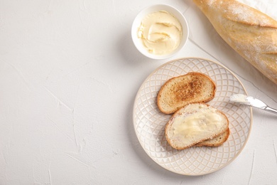 Photo of Tasty bread with butter served for breakfast on white table, top view. Space for text