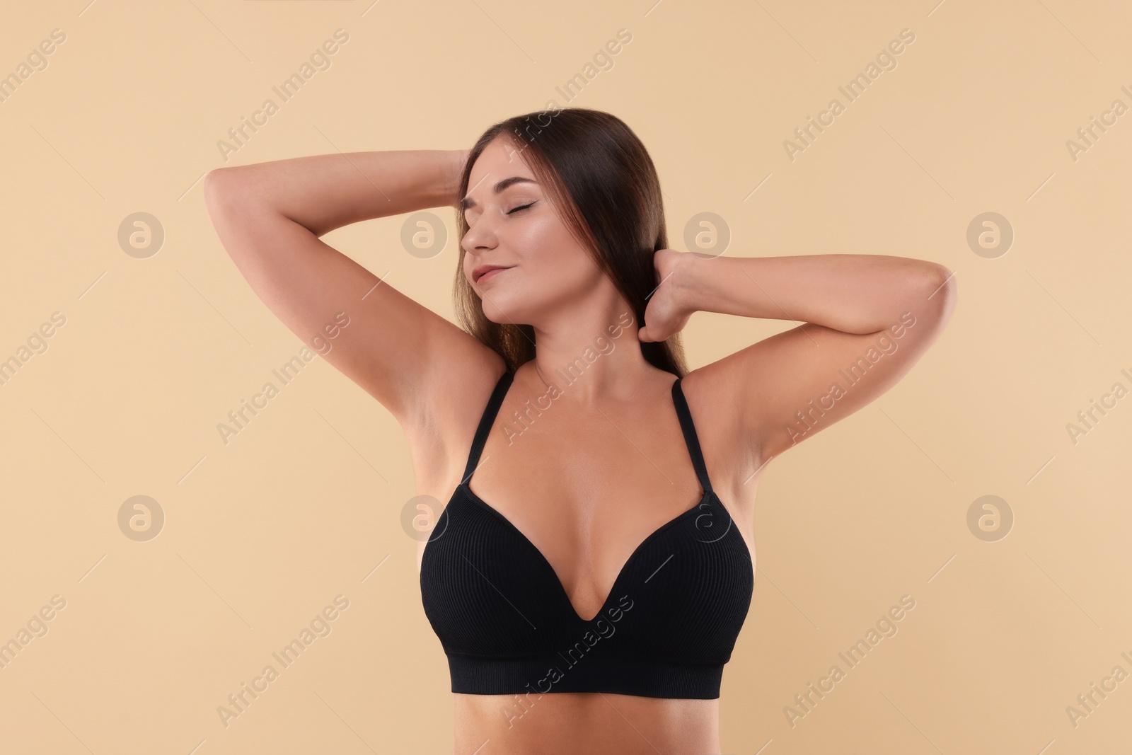 Photo of Portrait of young woman with beautiful breast on beige background