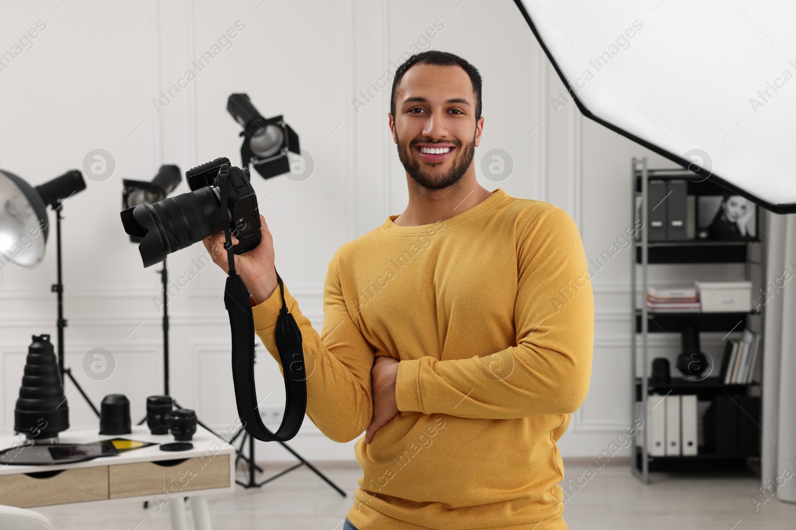 Photo of Young professional photographer with camera in modern photo studio